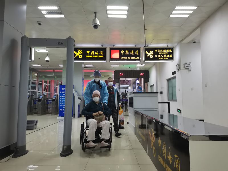 图为：青茂海关关员用轮椅护送赴澳就医旅客通关+黄锡龙摄